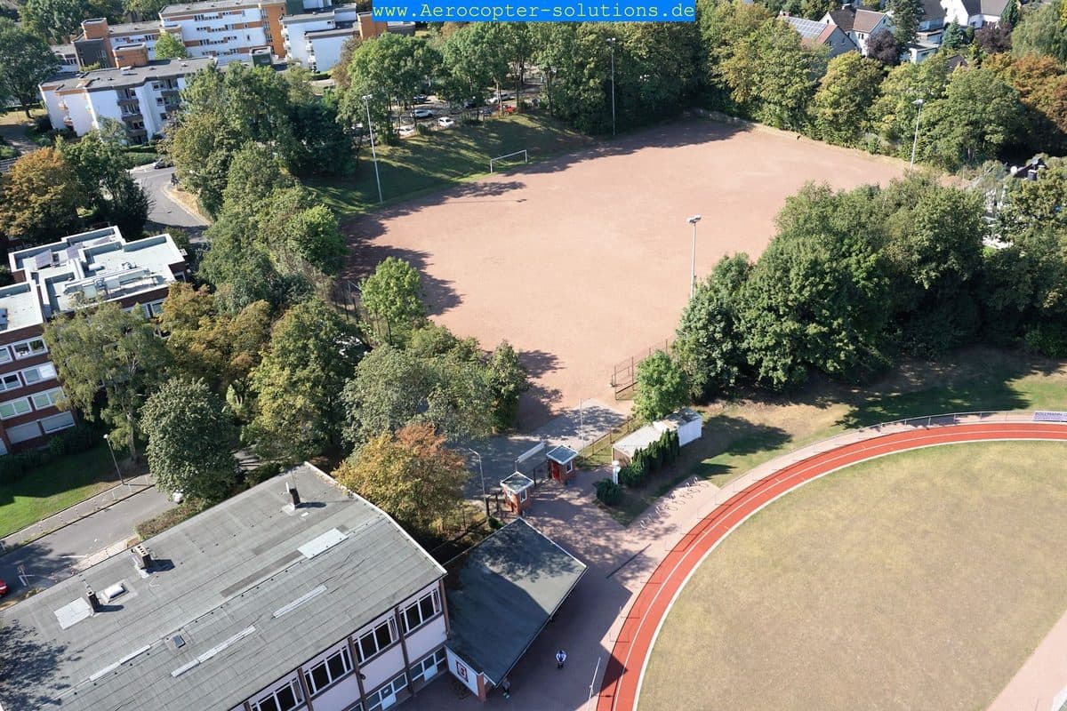 Blick von oben auf den Aschenplatz mit Vereinsheim und Bäumen