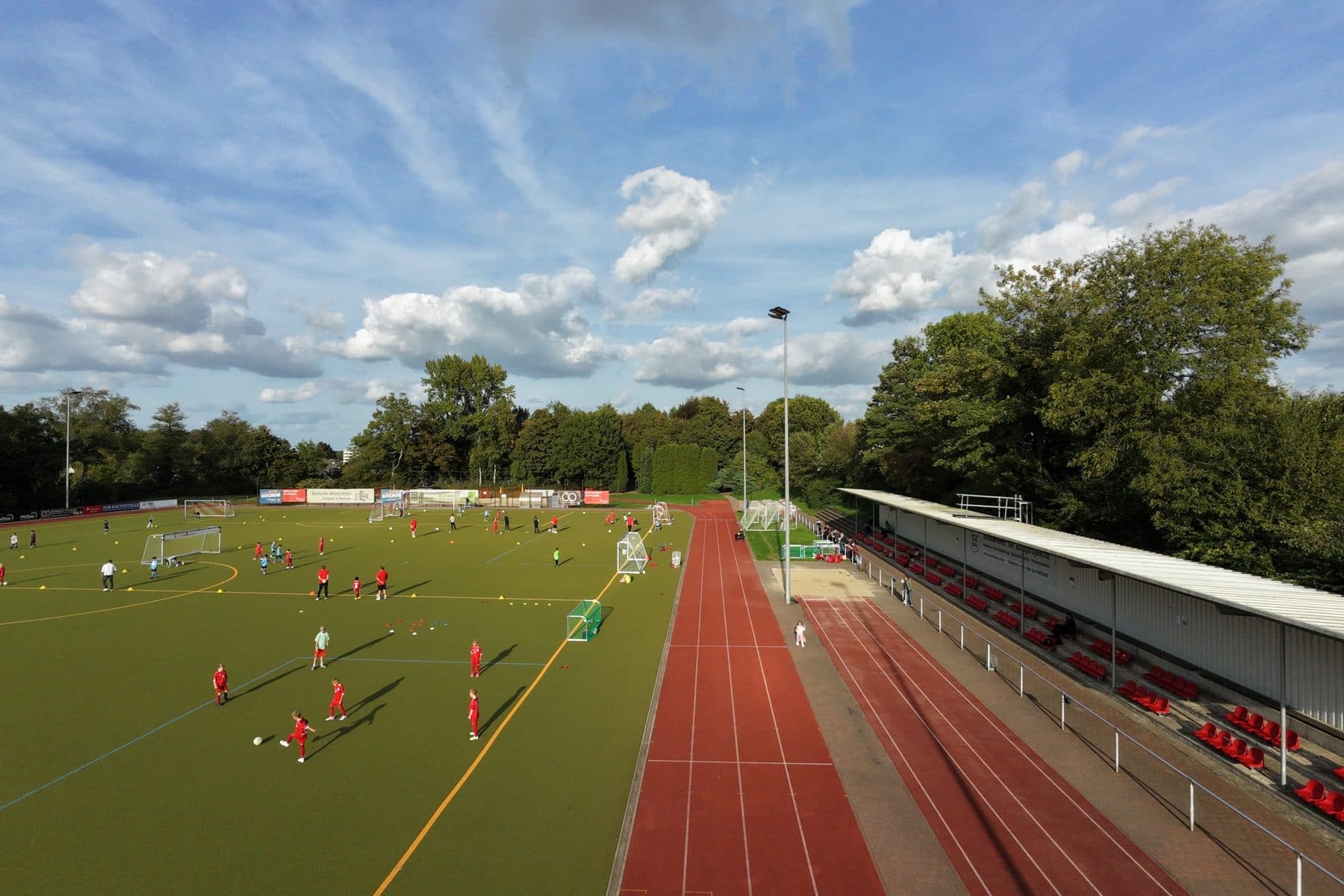 Drohnenaufnahme des Kunstrasenplatzes mit Tartanbahn und Stehtribüne im Sportpark